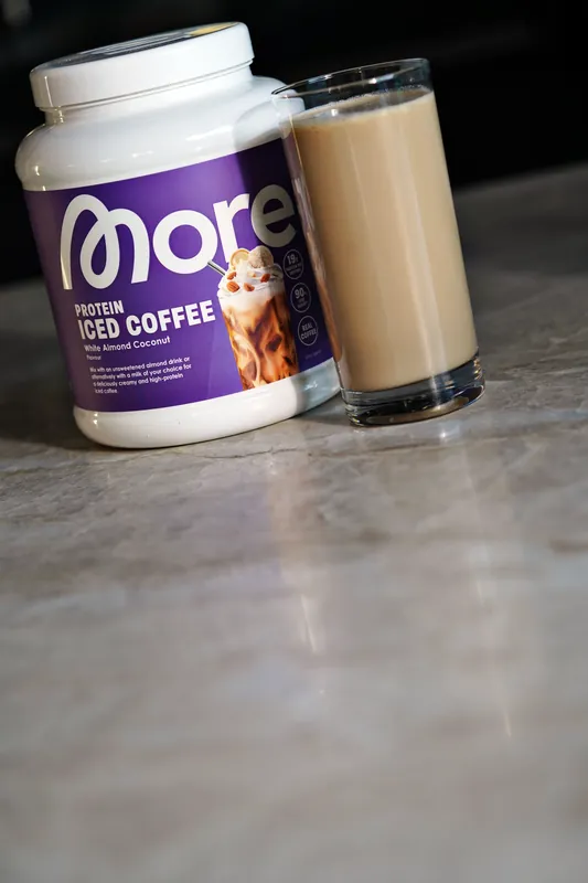 More Protein Iced Coffee – White Almond Coconut, avec un verre